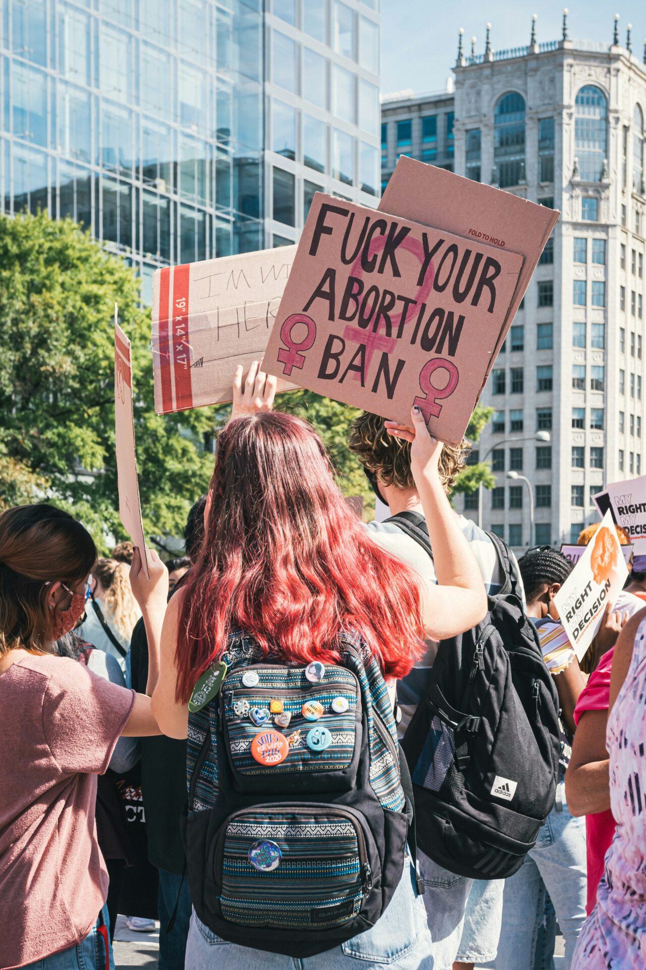 a group of people holding up signs and backpacks