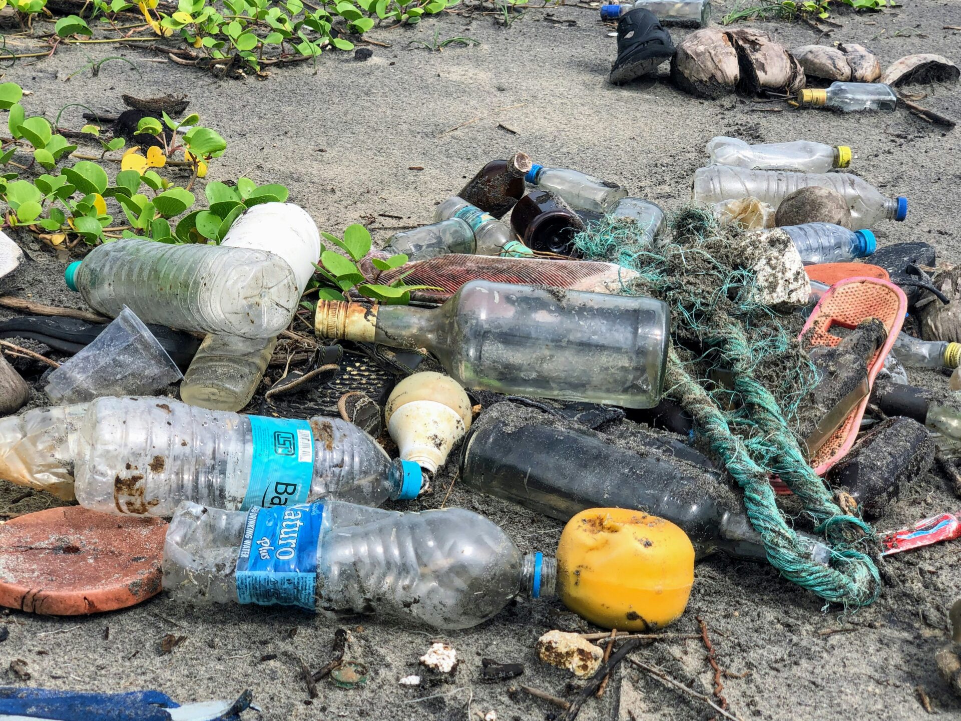 assorted garbage bottles on sandy surface