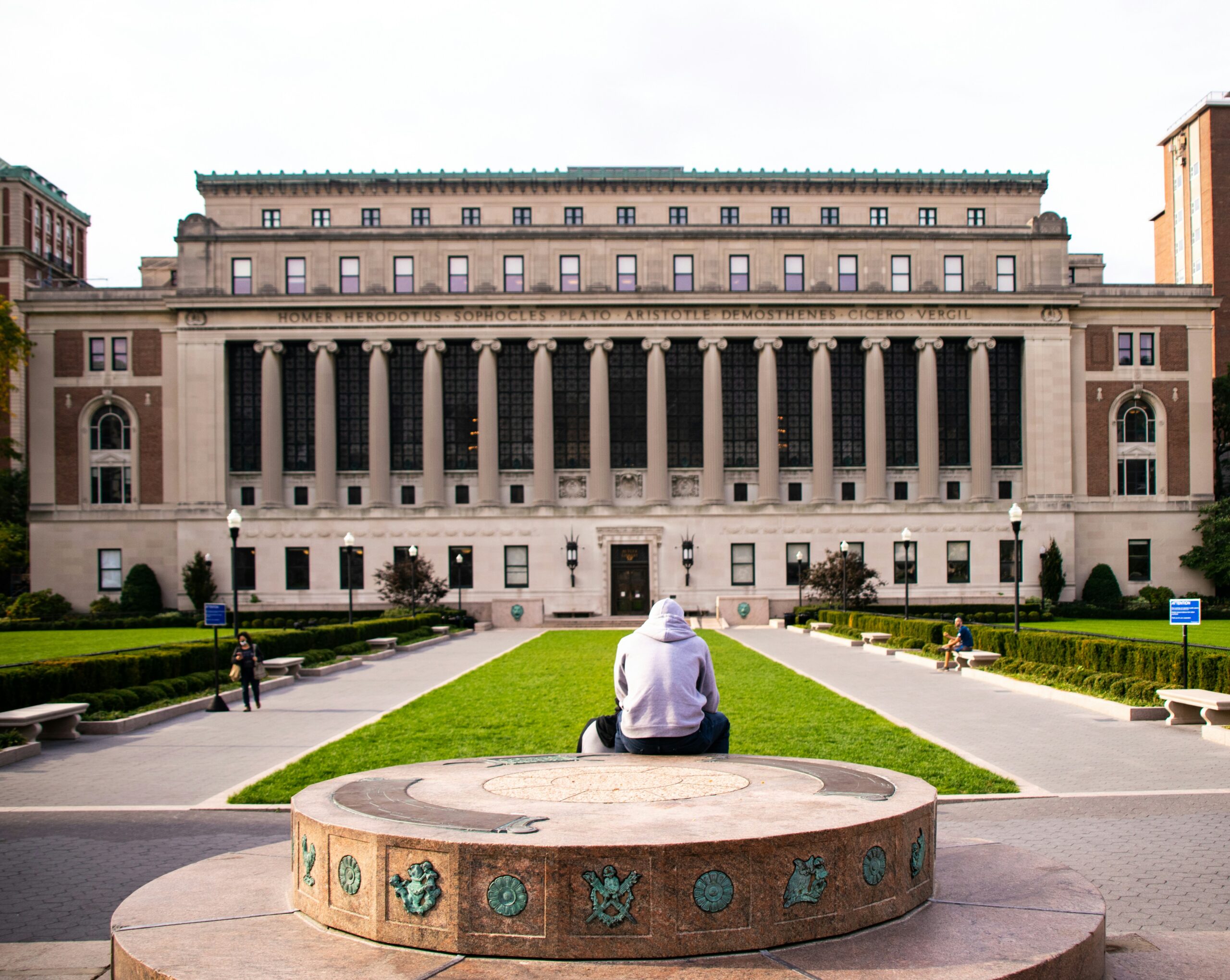 man in white dress shirt sitting on green grass field in front of white concrete building