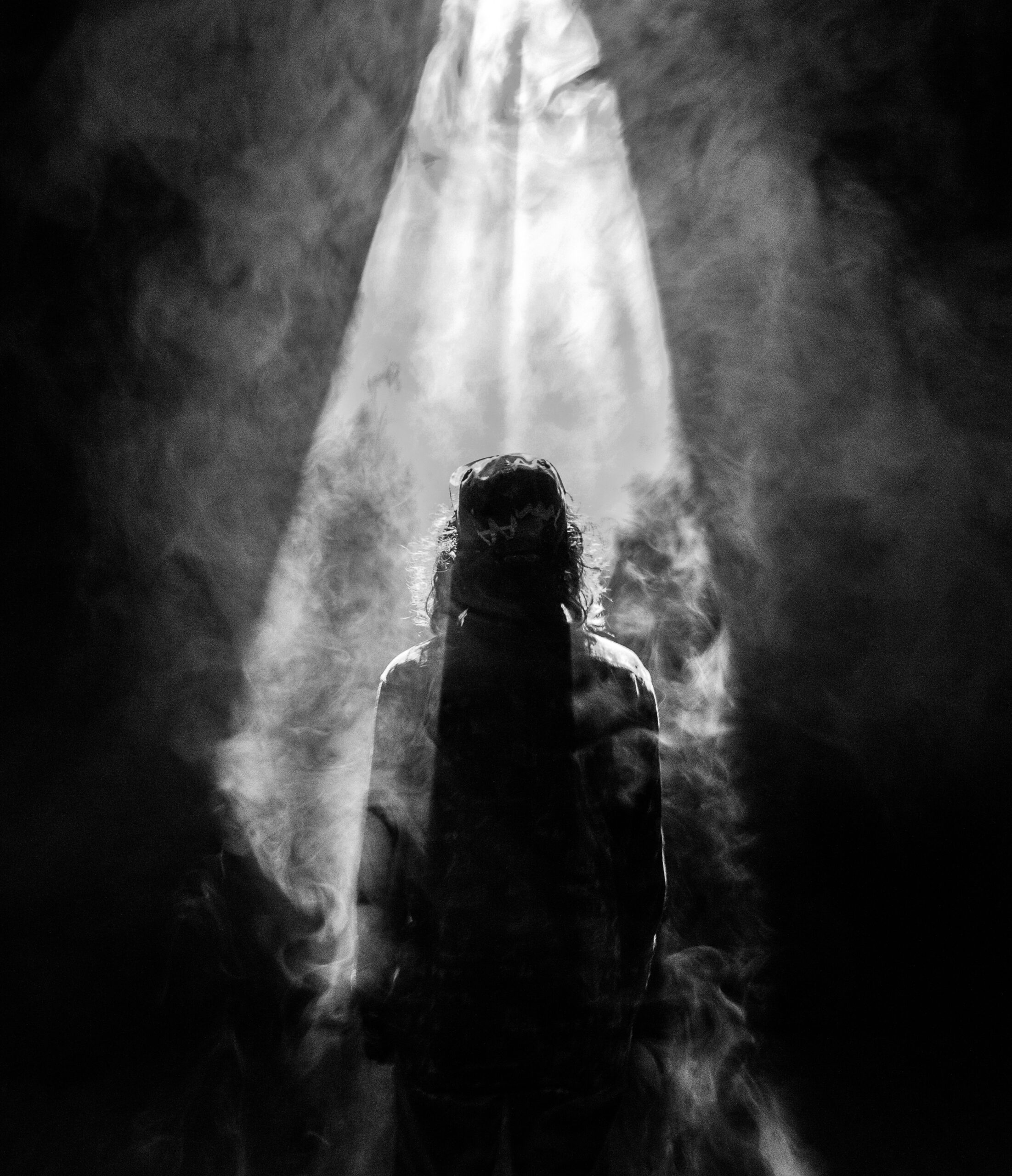 photograph of person facing opposite in smoky spotlight