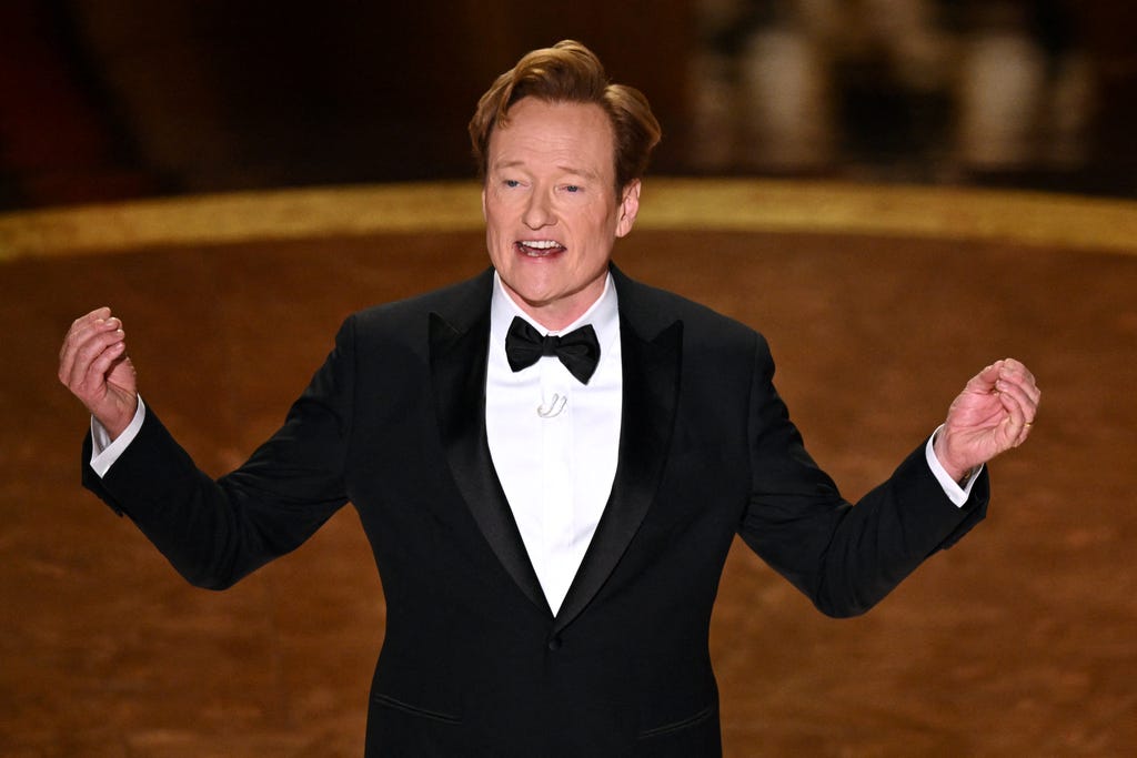 Oscars 2025, Academy Awards, Conan O'Brien, Jimmy Kimmel, A Real Pain, Nosferatu, The Brutalist, Conclave, Anora, Kieran Culkin, Adam Sandler, Emilia Pérez, Karla Sofía Gascón, opening monologue, jokes, host, winners, live updates, red carpet, Hollywood, musical number.

