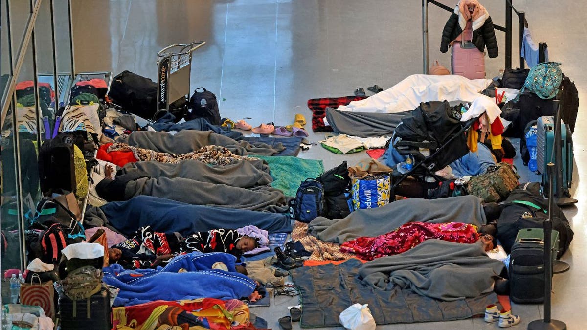 Migrant surge, sanctuary cities, Boston Logan International Airport, Ted Cruz, Senate Commerce Committee, Massachusetts Port Authority, Massport, Biden administration, open border policy, migrant crisis, airport shelter, migrant costs, taxpayer-funded accommodation, immigration, Donald Trump, border security.
